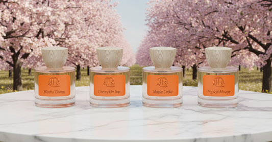Colección de perfumes de autor Joterc Parfums: Blissful Charm, Cherry On Top, Maple Cedar y Tropical Mirage sobre mesa de mármol con fondo de cerezos en flor