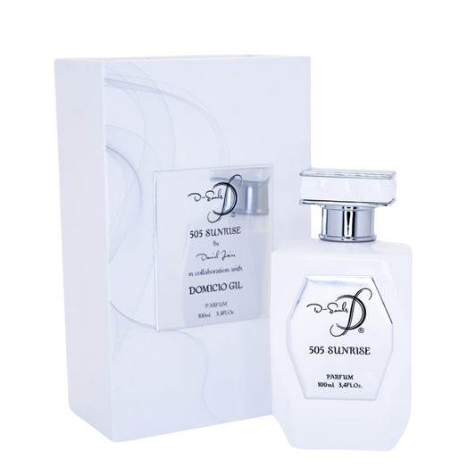El frasco, de líneas limpias y elegantes, presenta una forma octogonal y un acabado en blanco brillante, combinado con detalles metálicos en tono plateado que refuerzan su aspecto sofisticado. En la parte frontal de la botella se distingue una placa plateada que porta el nombre de la fragancia "505 SUNRISE" y las inscripciones relativas a su concentración y volumen.
Junto a la botella, se aprecia la caja, también en color blanco, con un diseño minimalista y delicadas líneas curvas sutilmente impresas.