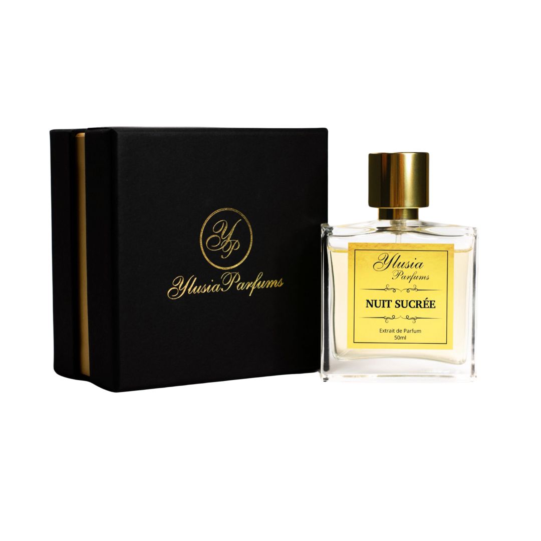 La imagen muestra el perfume "Nuit Sucrée" de Ylusia Parfums, presentado junto a su elegante caja negra con detalles dorados. El frasco tiene un diseño sofisticado y minimalista, con un cuerpo transparente que revela el líquido dorado en su interior, resaltando la etiqueta frontal en tono dorado con el nombre del perfume. El tapón metálico dorado complementa la estética lujosa del producto, ideal para transmitir exclusividad y refinamiento. La caja, con el logo de Ylusia Parfums estampado en dorado, refuer