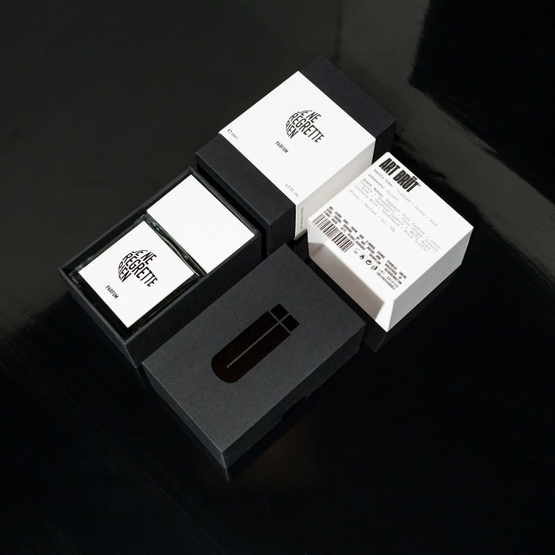 Detalle de packaging de Je Ne Regrette Rien: frasco y estuche sobre fondo negro
