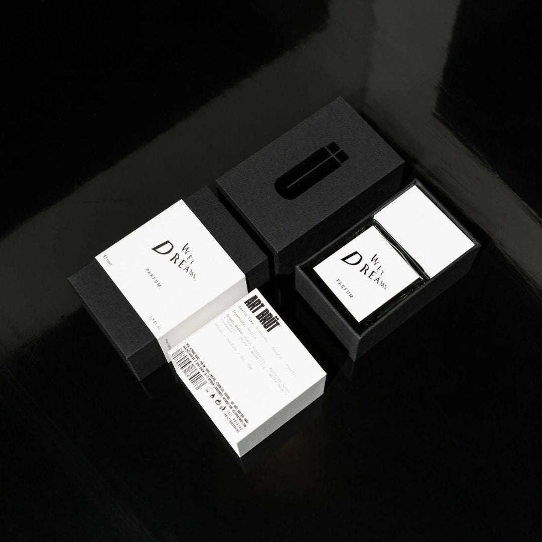 Estuche de Wet Dreams junto al frasco, packaging negro con ficha tecnica Art Brut